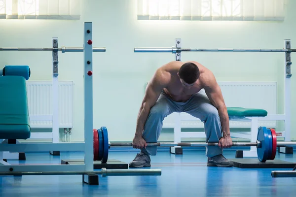 Man gör övningar med en skivstång i gymmet — Stockfoto