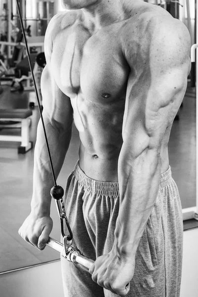 Člověk dělá cvičení na trenažéru pro svaly. — Stock fotografie