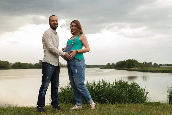 Těhotná pár na břehu jezera — Stock fotografie