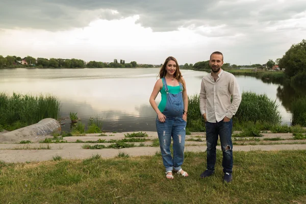 Pregnant couple on the lake shore — Stock Photo, Image