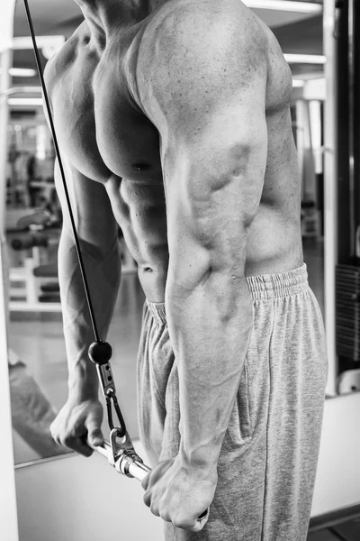 Человек делает упражнения на тренажере для мышц — стоковое фото