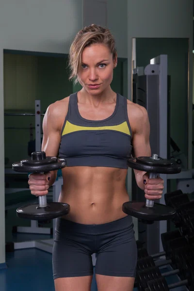 Sporty muscular blonde with dumbbells in the gym — Stock Photo, Image