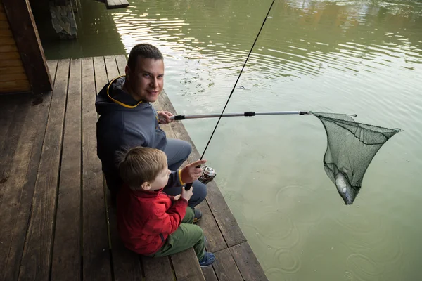 Padre e hijo en el proceso de captura de peces — Foto de Stock