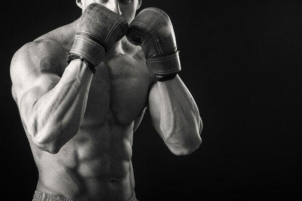 Athletic man in boxing gloves on a black background