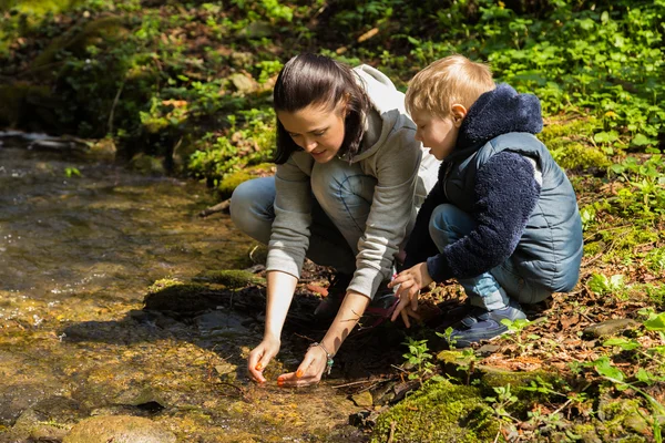 Äiti ja poika metsässä joen rannalla — kuvapankkivalokuva