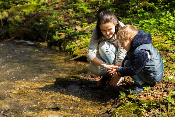 Äiti ja poika metsässä joen rannalla — kuvapankkivalokuva