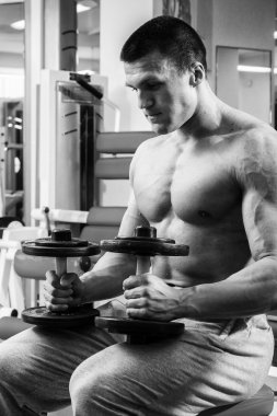 Dambıllarla egzersiz yapan adam.