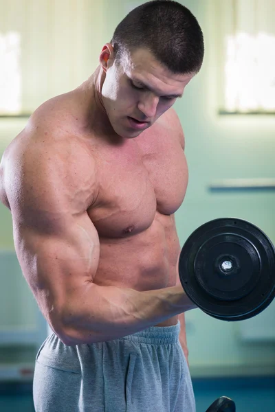 Athlète effectue des exercices dans la salle de gym — Photo