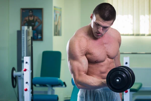 Athlète effectue des exercices dans la salle de gym — Photo
