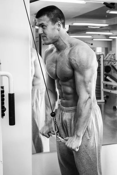 Athlète effectue des exercices dans la salle de gym — Photo