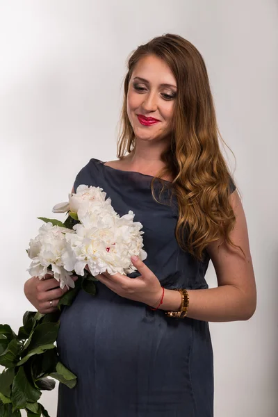 Piękna kobieta w ciąży z kwiatami — Zdjęcie stockowe