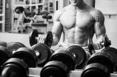 Adam dambıllarla egzersiz yapıyor.