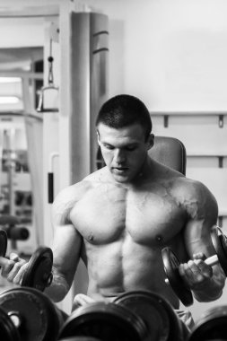 Dambıllarla egzersiz yapan adam.