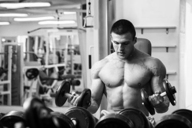 Dambıllarla egzersiz yapan adam.