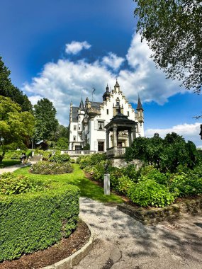Gotik tarzı şapel ve güller parçalı bulutlu bir gökyüzünün altında çiçek açıyor..