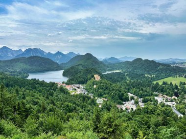 Bulutlu bir gökyüzünün altında göller, ormanlar ve dağlarla panoramik manzara.