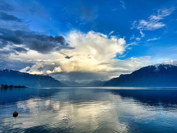 Sakin bir dağ gölünde, durgun sularda çarpıcı bulutlar ve yansımalarla manzaralı bir iskele..