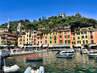 Parlak bir güneş ve dramatik bir gökyüzü altında renkli kıyı binaları, büyüleyici Akdeniz kasabasının üzerinde yükselen bir kilise kulesi..
