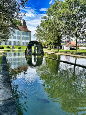 Güneşli bir günde göleti, heykeli ve yansıması olan tarihi saray.