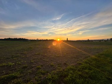 Sıcak altın ışıkla kırsal alanda gün batımı.