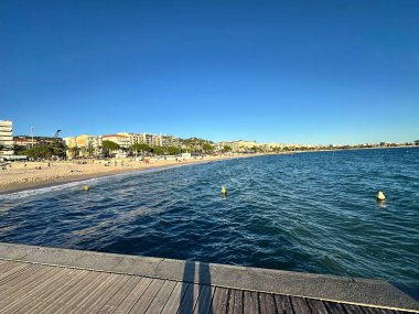 Yumuşak dalgalı mavi deniz, açık gökyüzü altında yelkenli ve yolcu gemisi.