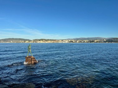 Yumuşak dalgalı mavi deniz, açık gökyüzü altında yelkenli ve yolcu gemisi.