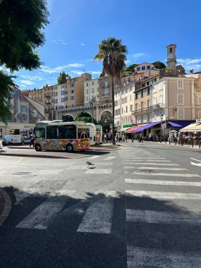 Renkli binaları, palmiye ağaçları ve parlak mavi gökyüzünün altında boyalı bir otobüsü olan güneşli şehir caddesi..
