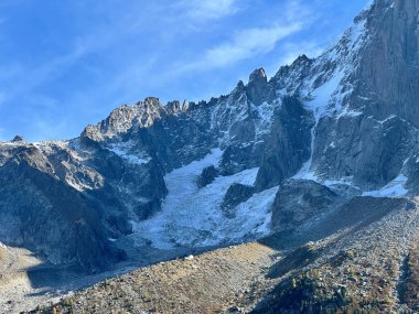 Buzul vadisi sarp kayalıklarla ve açık mavi gökyüzünün altında karla kaplı tepelerle çevrilidir..