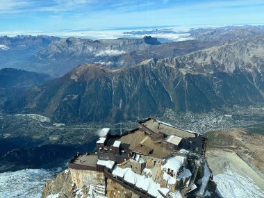 Mont Blanc 'ın görkemli manzarası ve bulutlu mavi gökyüzünün altındaki karla kaplı tepeler, gösterişli buzullar ve engebeli dağlık arazi.