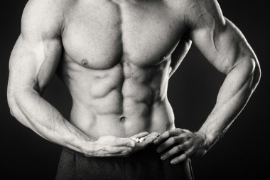 Profesyonel vücut geliştirmeci bedeni koyu arka plan üzerinde gösterir.