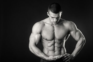 Profesyonel vücut geliştirmeci bedeni koyu arka plan üzerinde gösterir.