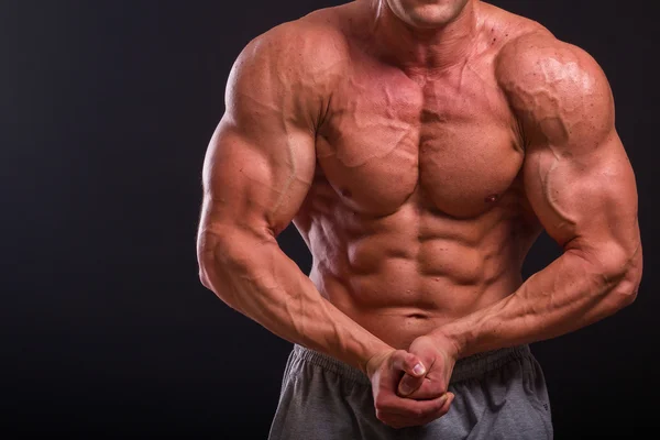 Professional bodybuilder shows his body on a dark background — Stock Photo, Image