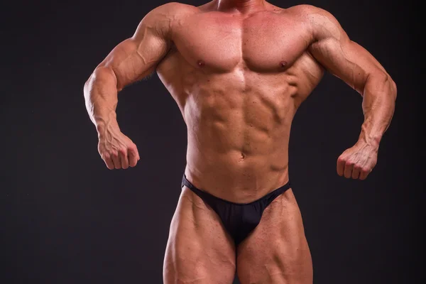 Επαγγελματία bodybuilder δείχνει το σώμα του σε σκούρο φόντο — Φωτογραφία Αρχείου