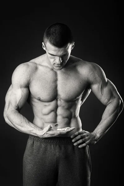Professionele bodybuilder toont zijn lichaam op een donkere achtergrond — Stockfoto