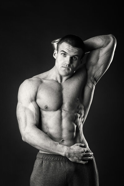 Professional bodybuilder shows his body on a dark background