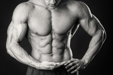 Profesyonel vücut geliştirmeci bedeni koyu arka plan üzerinde gösterir.