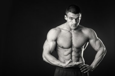 Profesyonel vücut geliştirmeci bedeni koyu arka plan üzerinde gösterir.