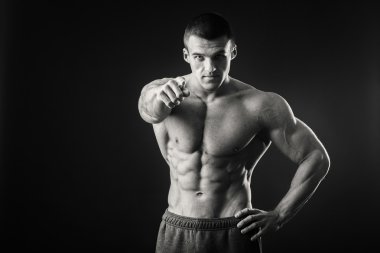 Profesyonel vücut geliştirmeci bedeni koyu arka plan üzerinde gösterir.