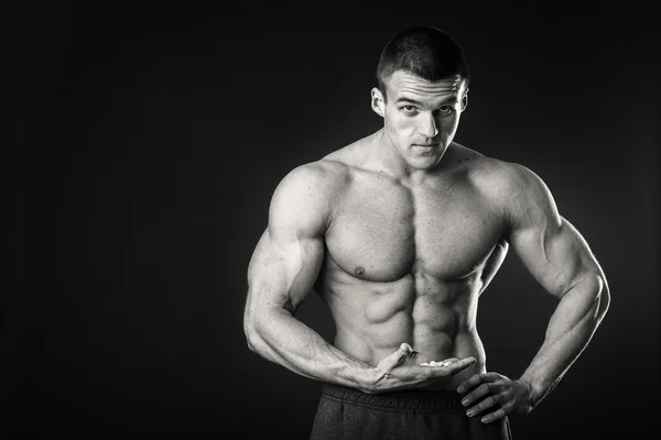 Bodybuilder professionista mostra il suo corpo su uno sfondo scuro — Foto Stock