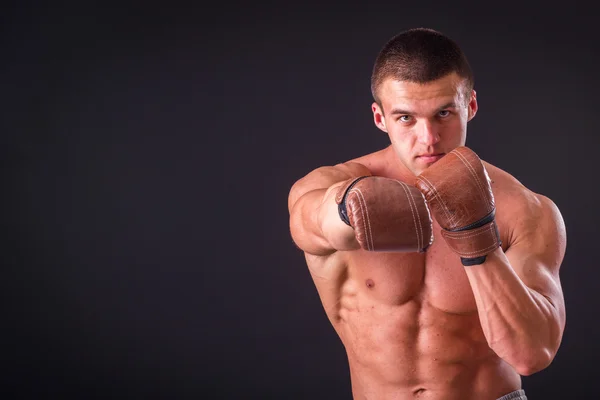 Bodybuilder professionnel montre son corps sur un fond sombre — Photo