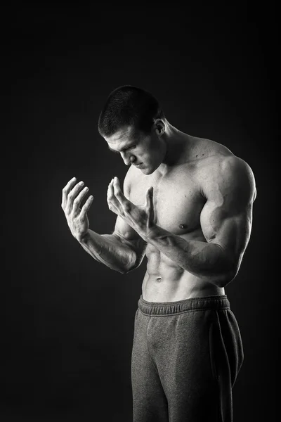 Fisiculturista profissional mostra seu corpo em um fundo escuro — Fotografia de Stock