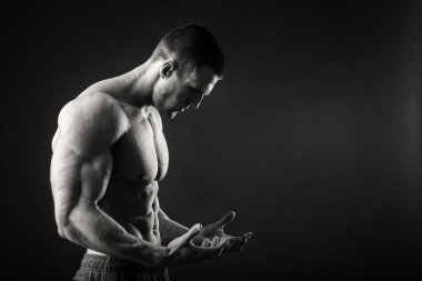 Profesyonel vücut geliştirmeci bedeni koyu arka plan üzerinde gösterir.