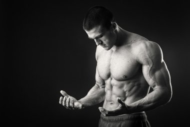 Profesyonel vücut geliştirmeci bedeni koyu arka plan üzerinde gösterir.