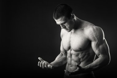 Profesyonel vücut geliştirmeci bedeni koyu arka plan üzerinde gösterir.