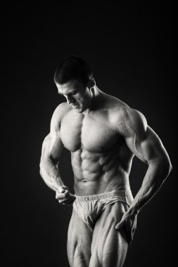 Profesyonel vücut geliştirmeci bedeni koyu arka plan üzerinde gösterir.