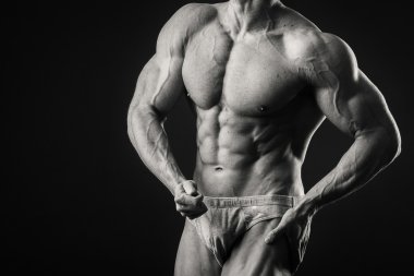 Profesyonel vücut geliştirmeci bedeni koyu arka plan üzerinde gösterir.