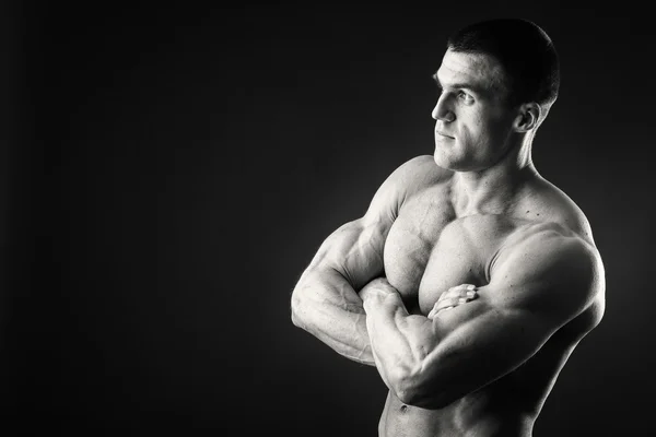 Profi-Bodybuilder zeigt seinen Körper auf dunklem Hintergrund — Stockfoto