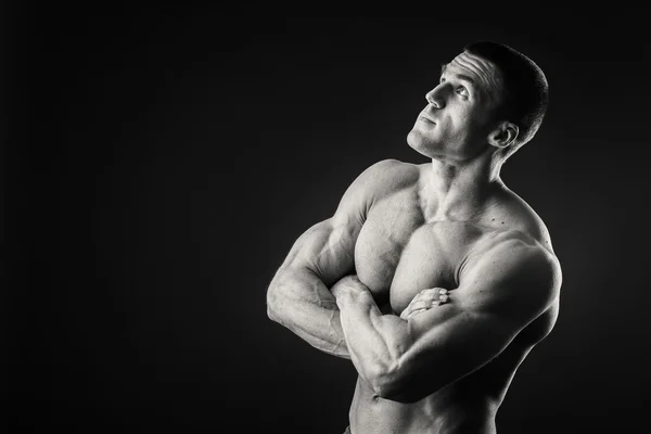 Profi-Bodybuilder zeigt seinen Körper auf dunklem Hintergrund — Stockfoto