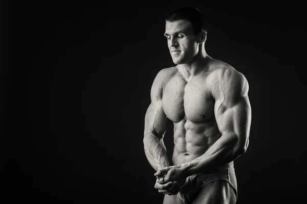 Profi-Bodybuilder zeigt seinen Körper auf dunklem Hintergrund — Stockfoto