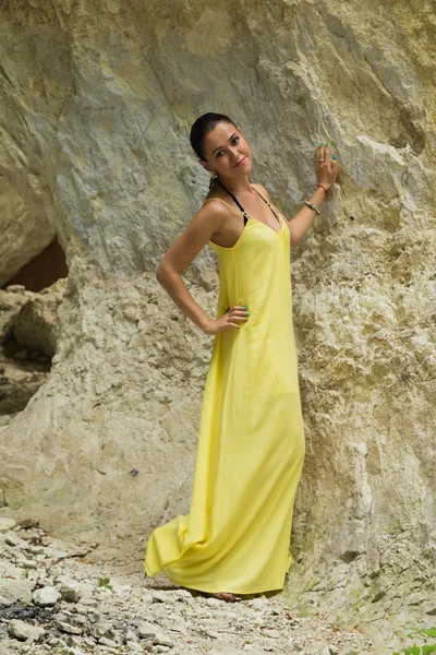 Belle brune en robe jaune sur fond de rocher — Photo